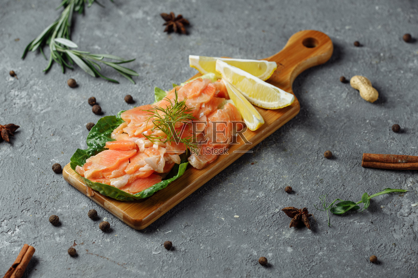 在木板上放上几片配莳萝和柠檬的油炸三文鱼照片摄影图片