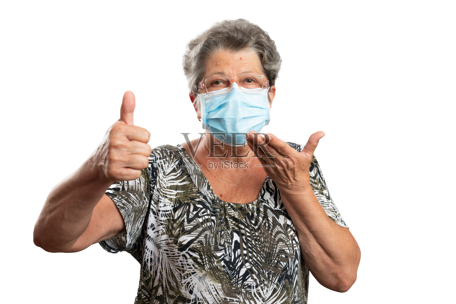 老妇人指着外科口罩做拇指向上的手势照片摄影图片