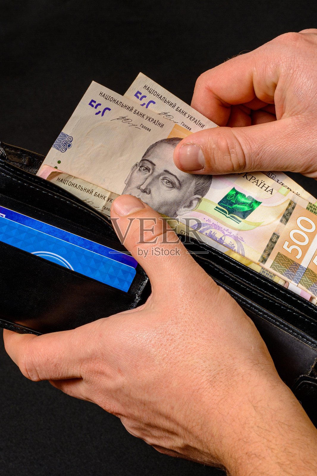 当一个男人掏出一张500格里夫纳的钞票时,他的钱包里的特写镜头。照片摄影图片