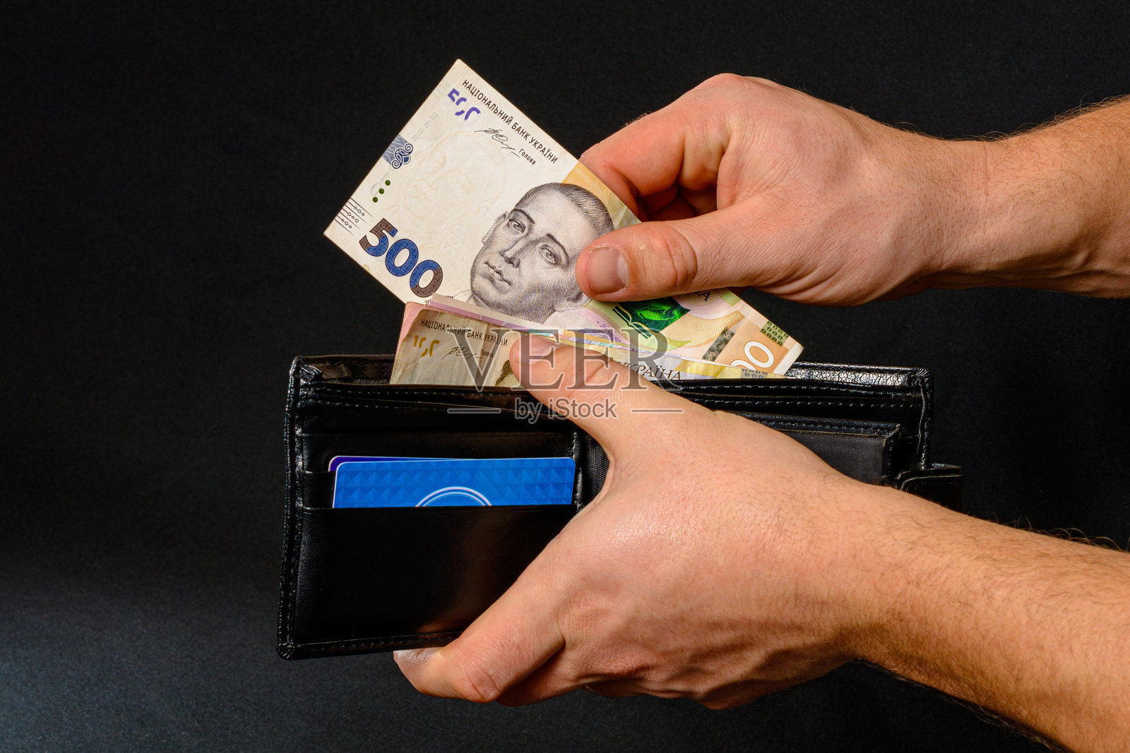 黑色钱包里的乌克兰格里夫尼亚,被一个男人拿在手里。照片摄影图片