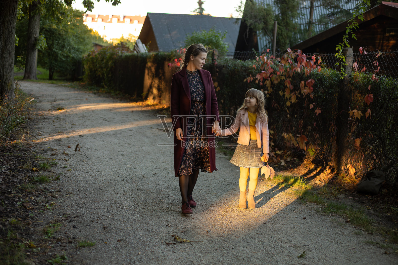 家庭、季节和人的概念——快乐的母亲和小女儿沿着村庄路边的秋天公园散步照片摄影图片