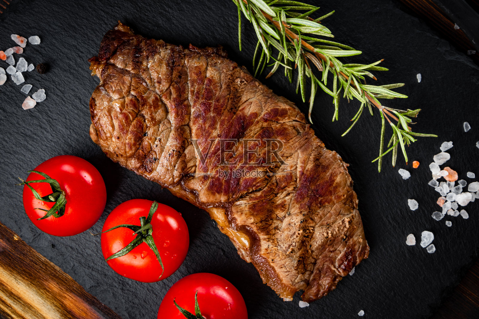 烤牛排与香料在一个黑色的背景,近照片摄影图片