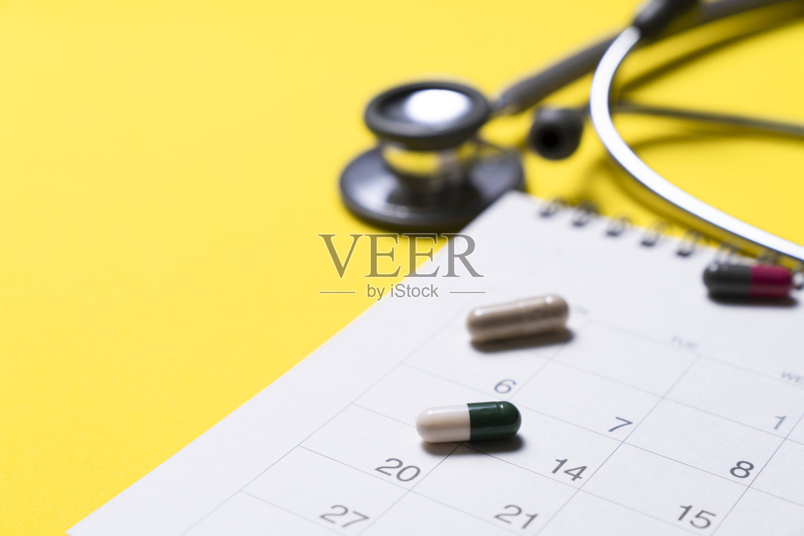 听诊器、药物和日历在黄色背景上的关闭,时间表检查健康的概念照片摄影图片