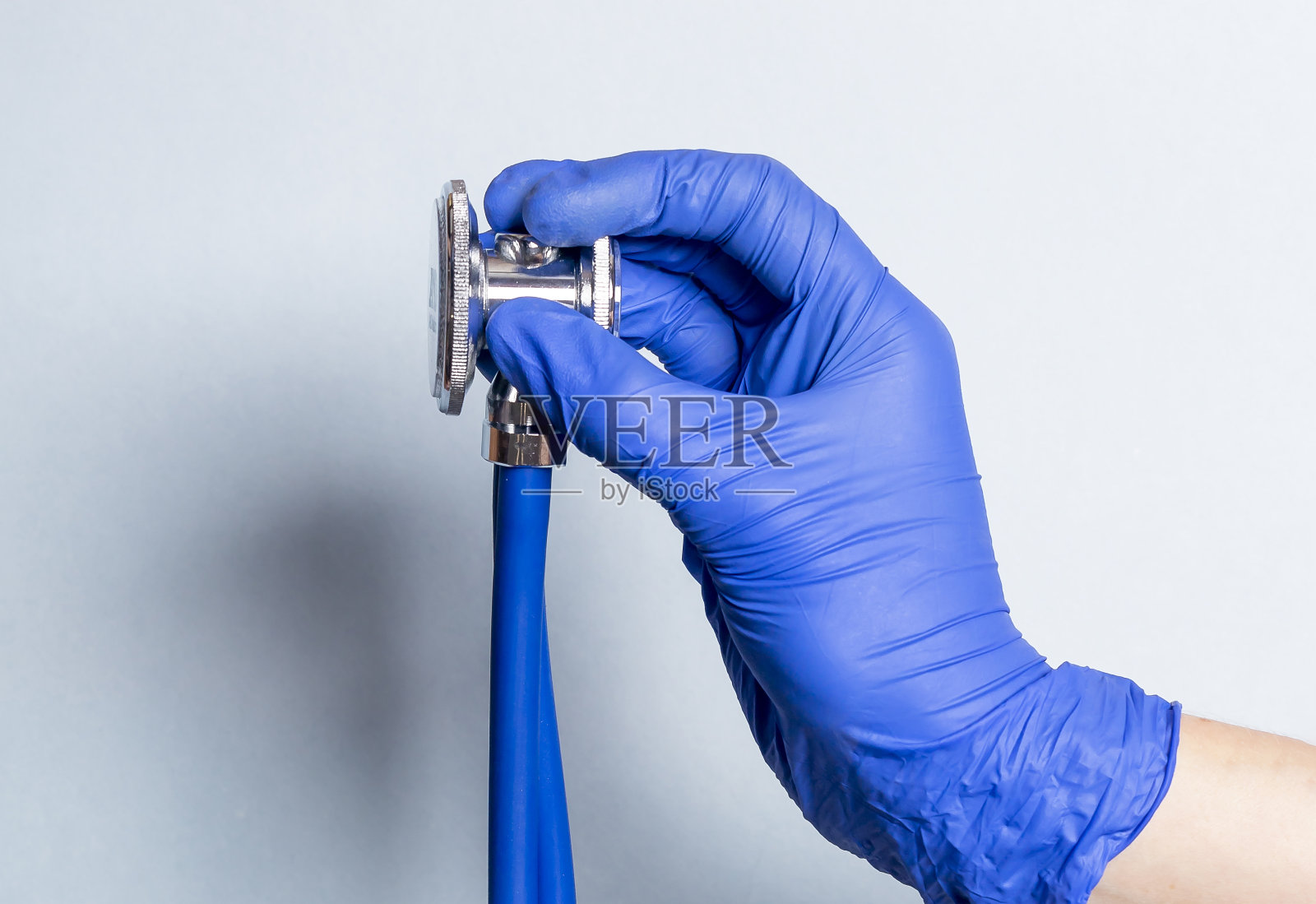 手持听诊器手套,蓝色背景照片摄影图片