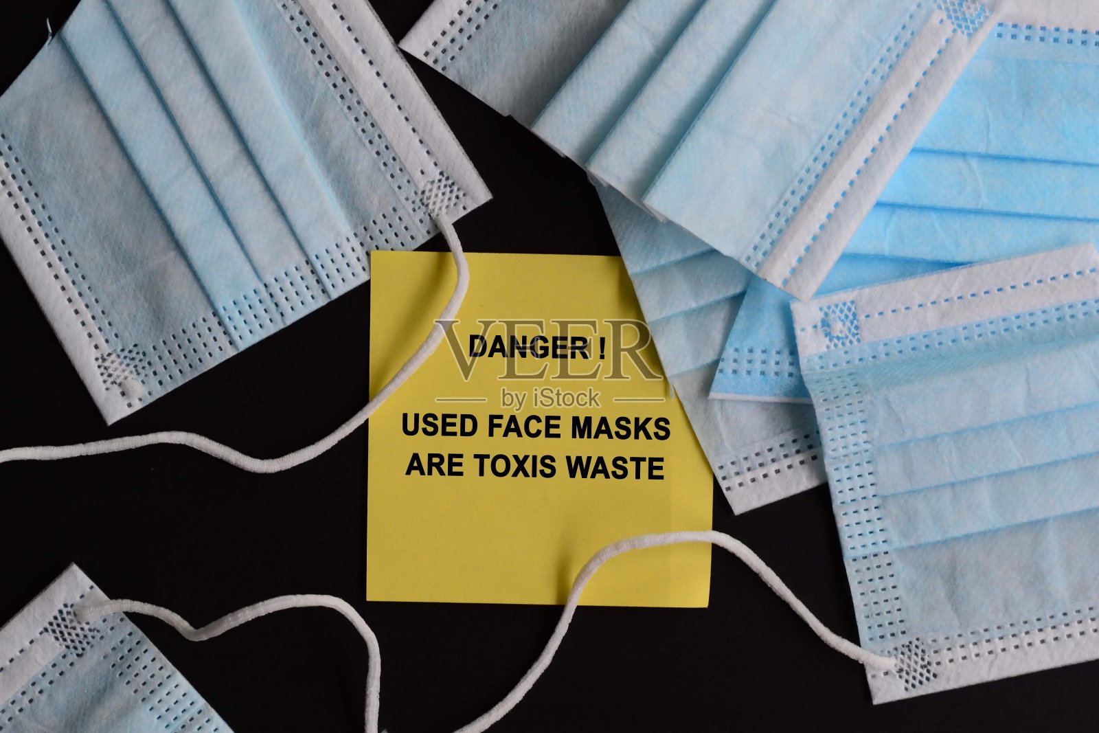 用黑色背景的黄色便签上警告及处置口罩的建议照片摄影图片