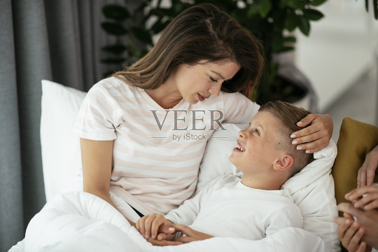 母亲和儿子在床上享受。照片摄影图片