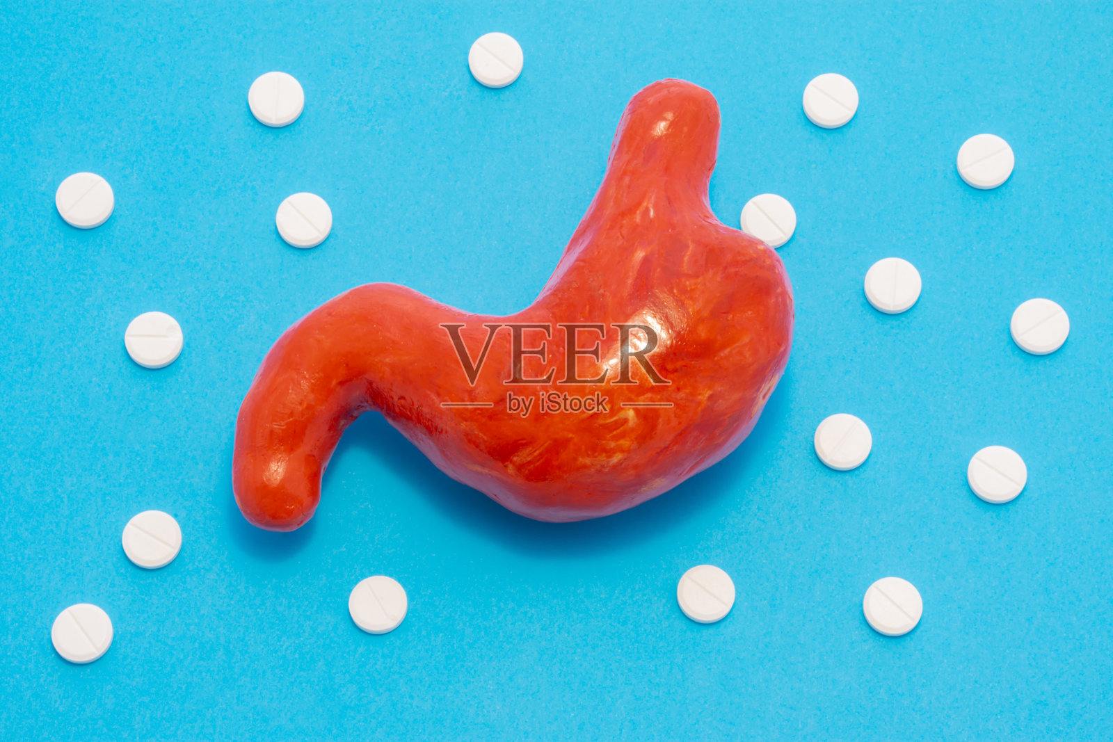 解剖图的胃,相同形状的活器官,是在蓝色的背景包围着白色的丸子,成分波尔卡圆点点缀。用于胃肠病学的照片,治疗的概念照片摄影图片