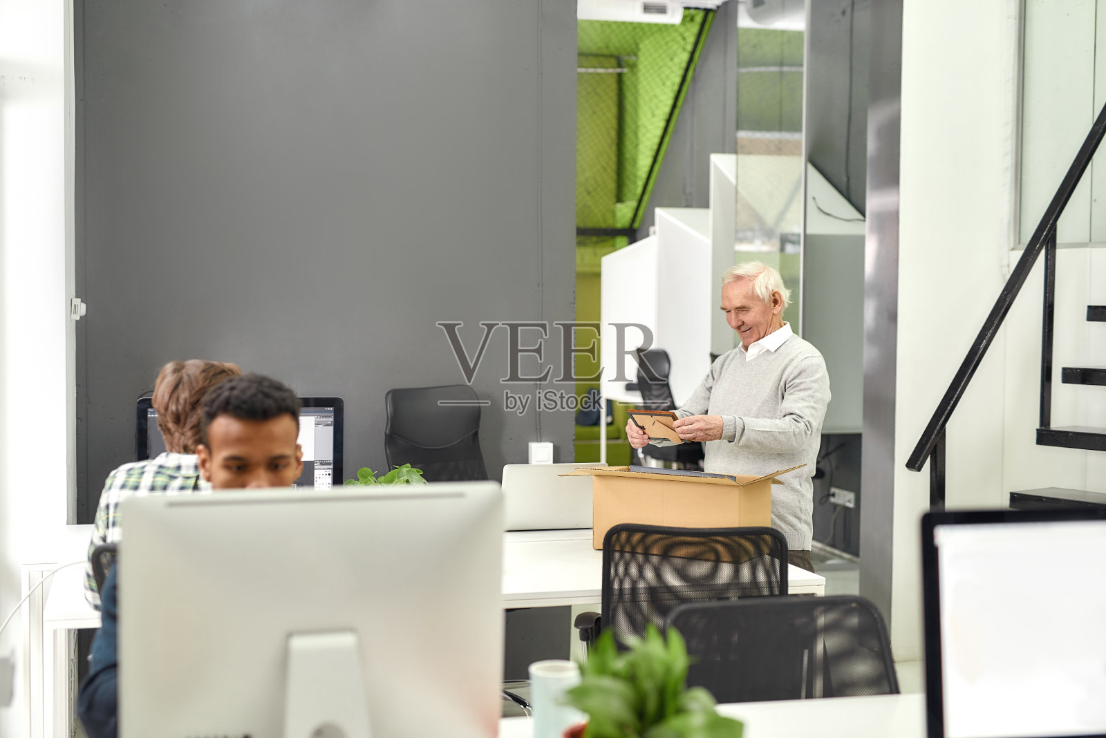 新员工中年男子,高级实习生一边从打开的盒子里拿出个人物品,一边看着家人的照片,为第一天上班做准备照片摄影图片