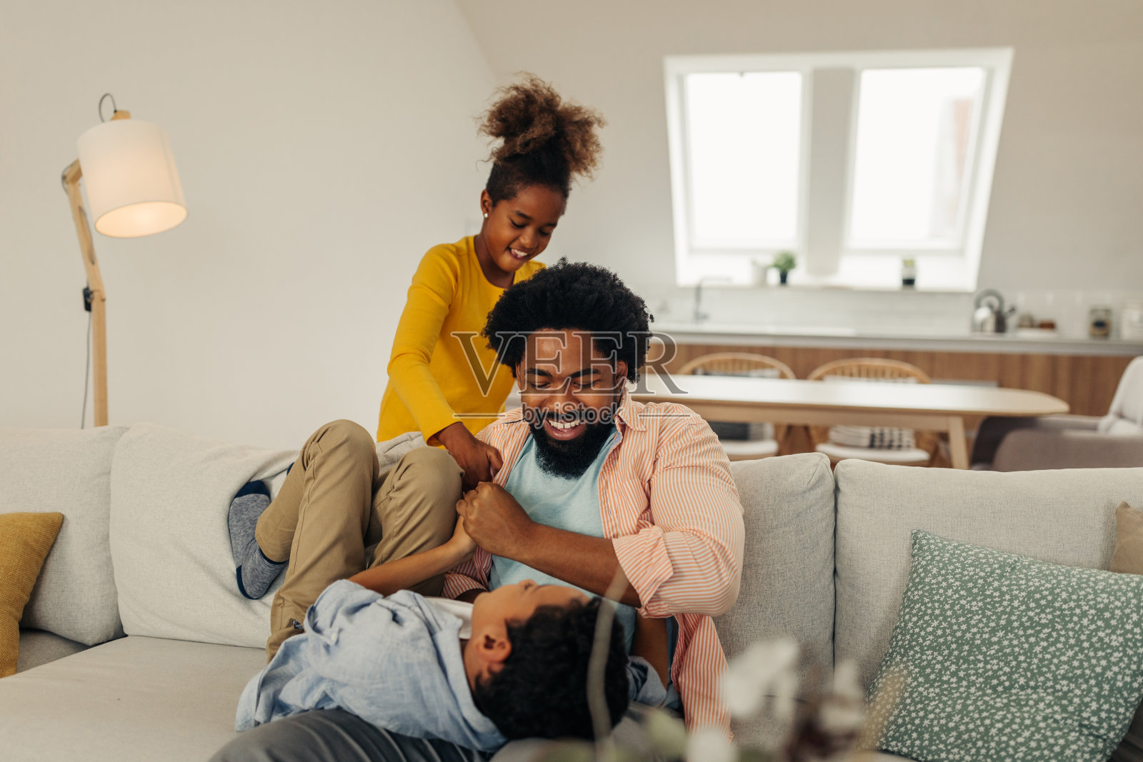 一个黑人家庭在客厅里。父亲在逗他的孩子照片摄影图片