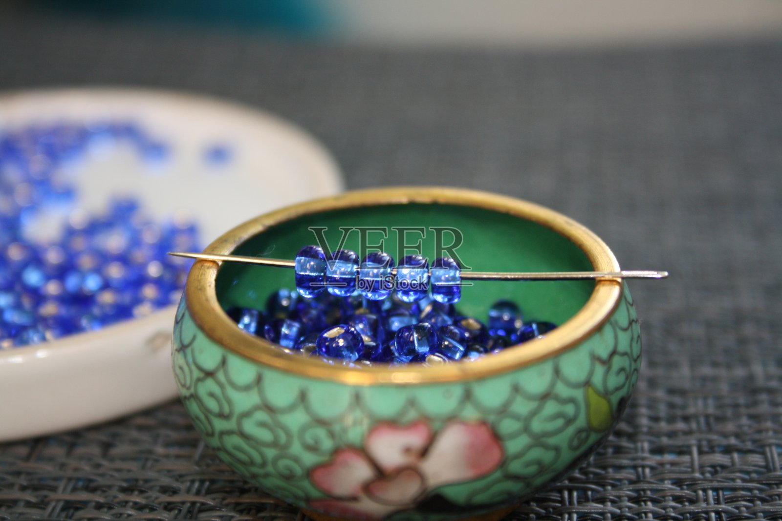 玻璃碟上的蓝色装饰珠。照片摄影图片