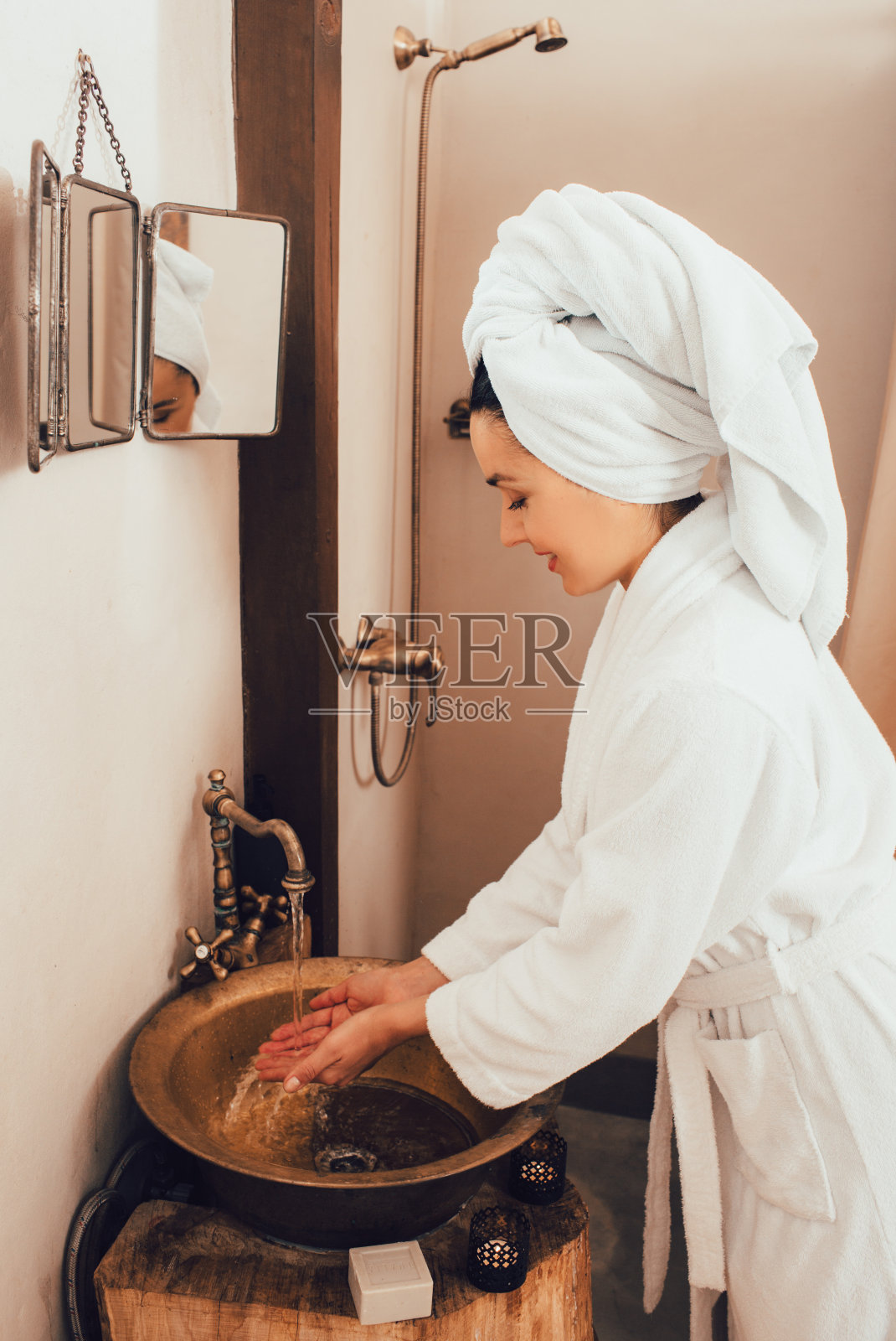 美丽的女子头戴毛巾,在水疗中心对身体进行油按摩后洗手照片摄影图片