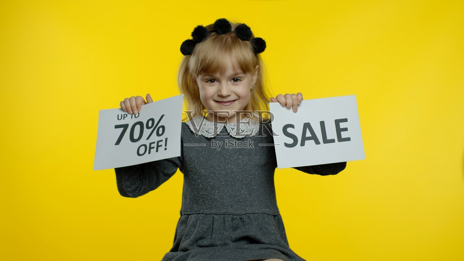 微笑的小女孩旁边有“高达七折”的题词。学龄前儿童的孩子庆祝照片摄影图片