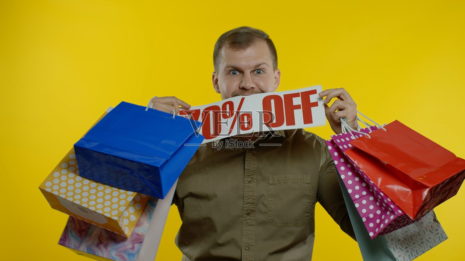 一名男子展示了“高达七折”的标语和购物袋,看起来对低价很满意照片摄影图片