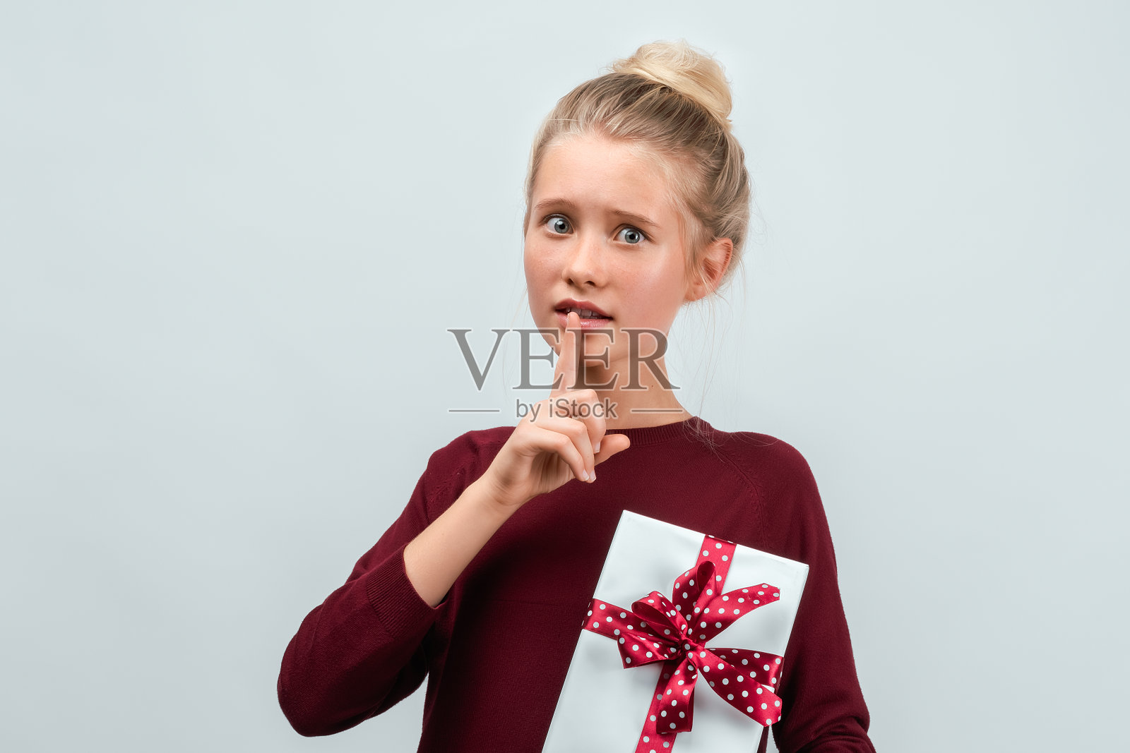 快乐的金发女孩的肖像拿着用丝带装饰的礼物。工作室拍摄白色背景照片摄影图片