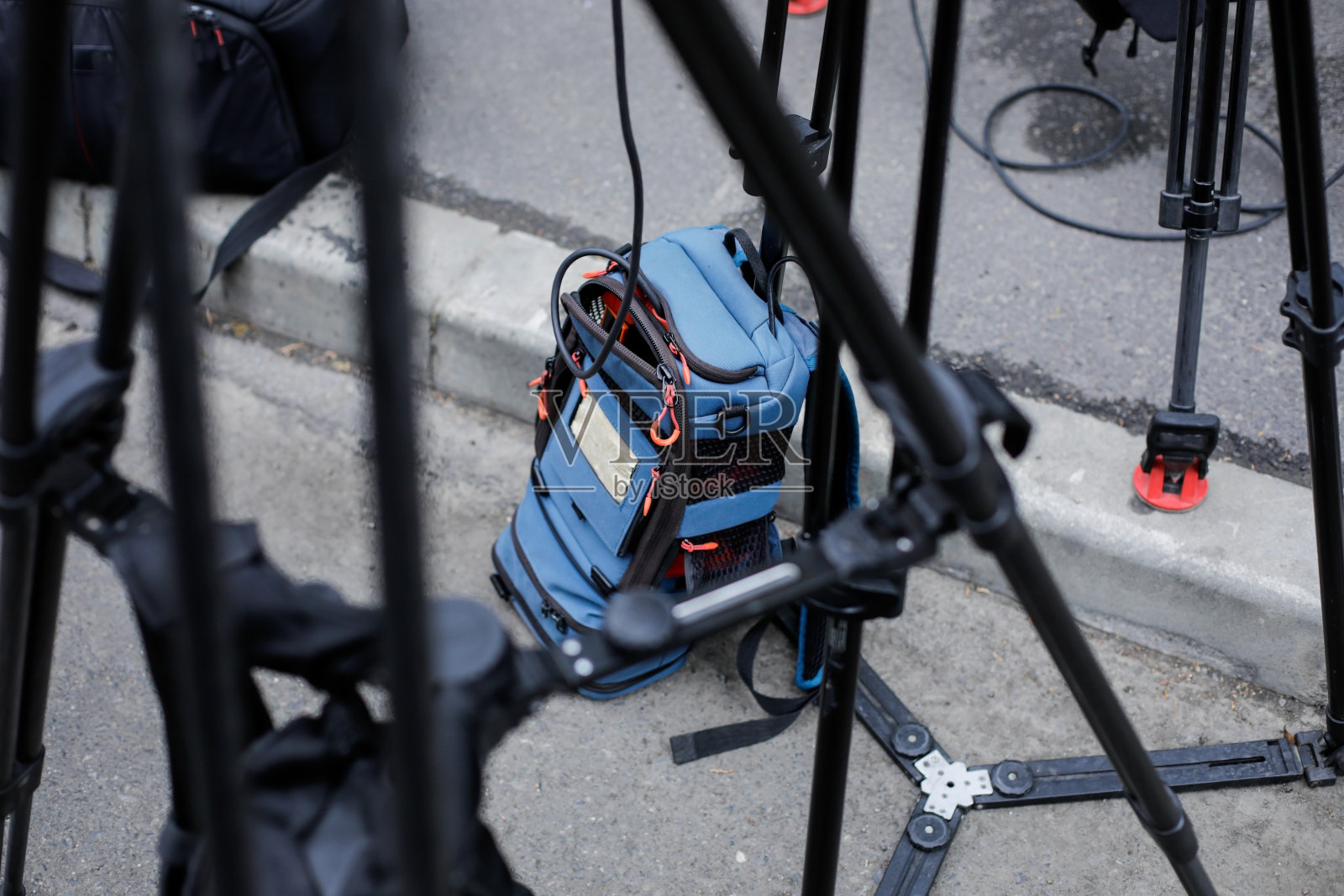 电视摄影师背包里的直播视频传输和直播流媒体设备,放在三脚架之间。照片摄影图片