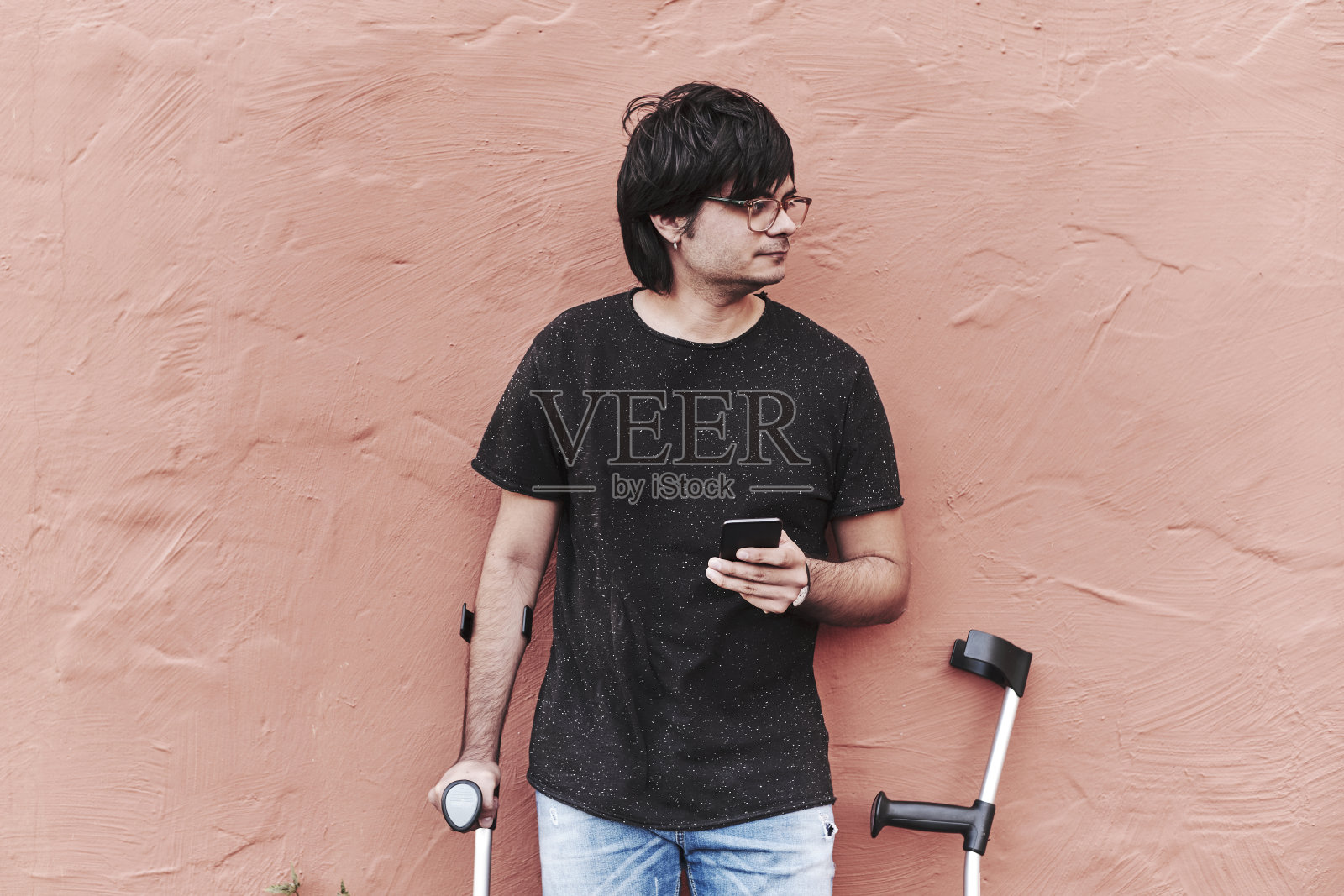 用拐杖和电话的快乐年轻人的肖像照片摄影图片