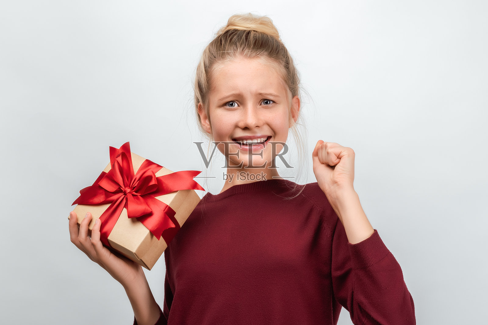 快乐的金发女孩的肖像拿着用丝带装饰的礼物。工作室拍摄白色背景照片摄影图片