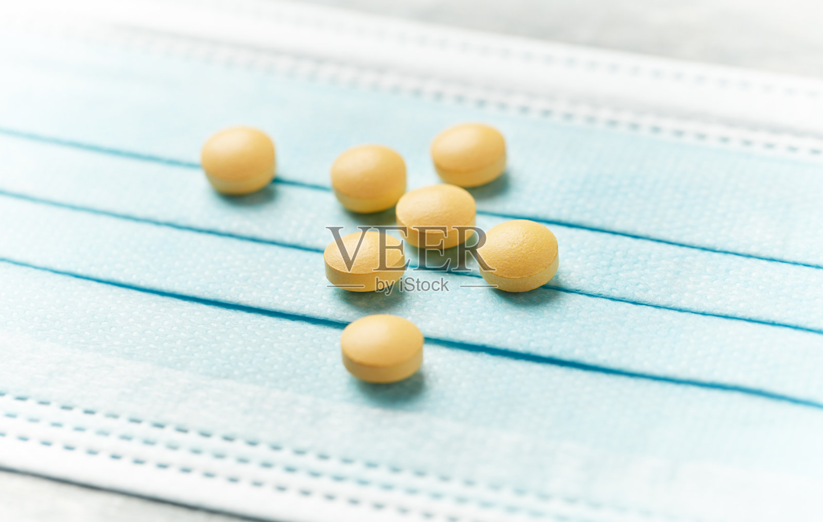 医用口罩上的维生素C片。明亮的木制背景。关闭了。照片摄影图片