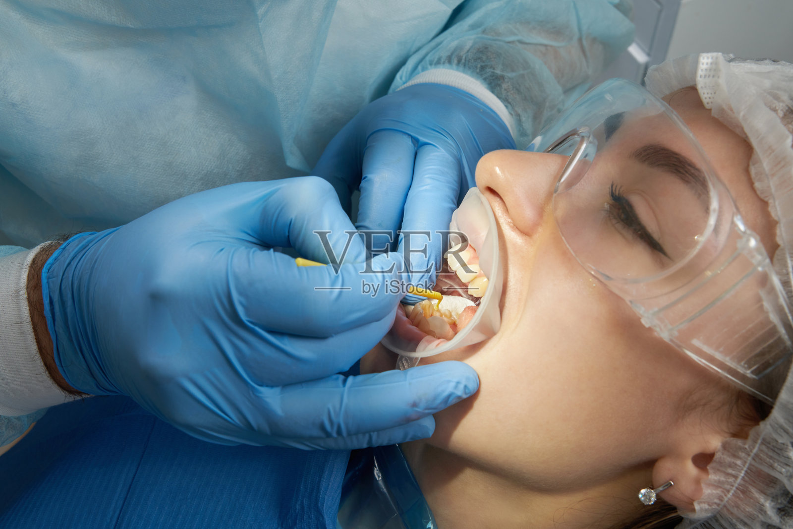 牙医正在给一位女病人做牙科治疗。牙科医生在现代牙科诊所检查病人的牙齿照片摄影图片