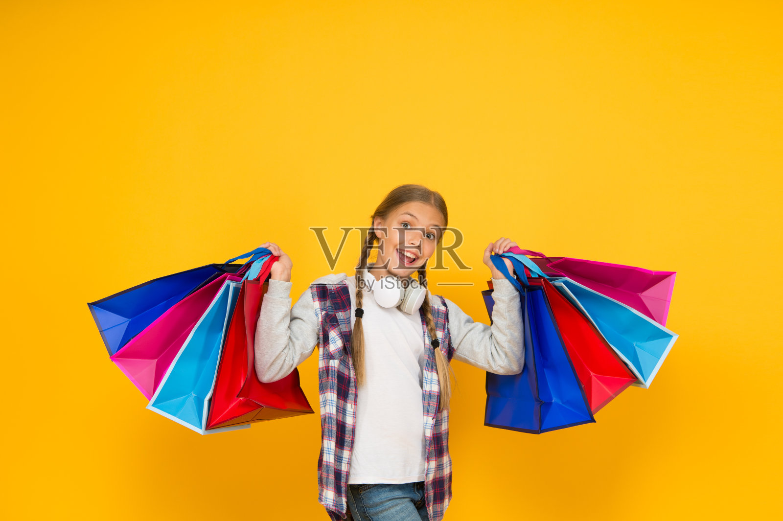 节日的准备和庆祝。黑色星期五购物和打折。上瘾的消费者。进入购物。快乐的孩子与纸袋。小女孩微笑着,黄色的背景是购物袋照片摄影图片