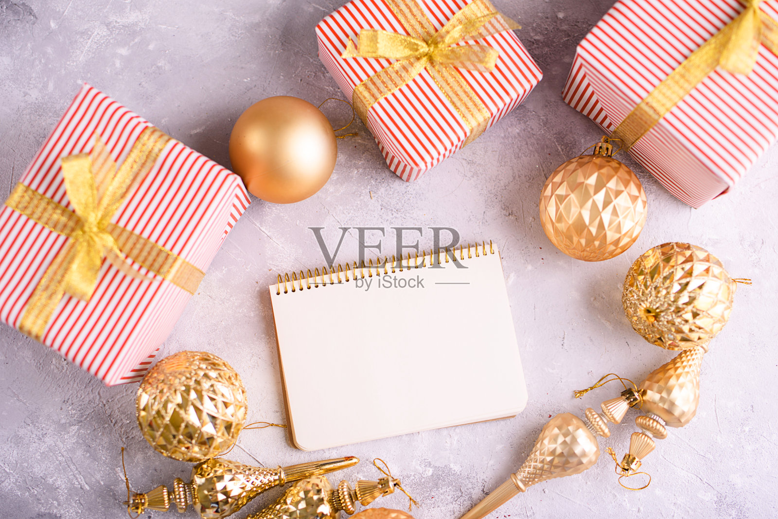 漂亮的笔记本,白色的空床单和金色的春天,圣诞树上的金色玩具,装饰和包装的漂亮礼物。从高处俯瞰照片摄影图片