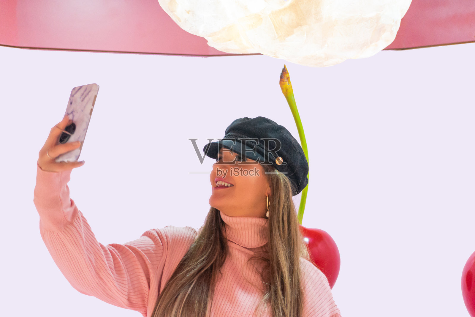 戴着帽子的年轻女子正在和巨大的樱桃自拍照片摄影图片