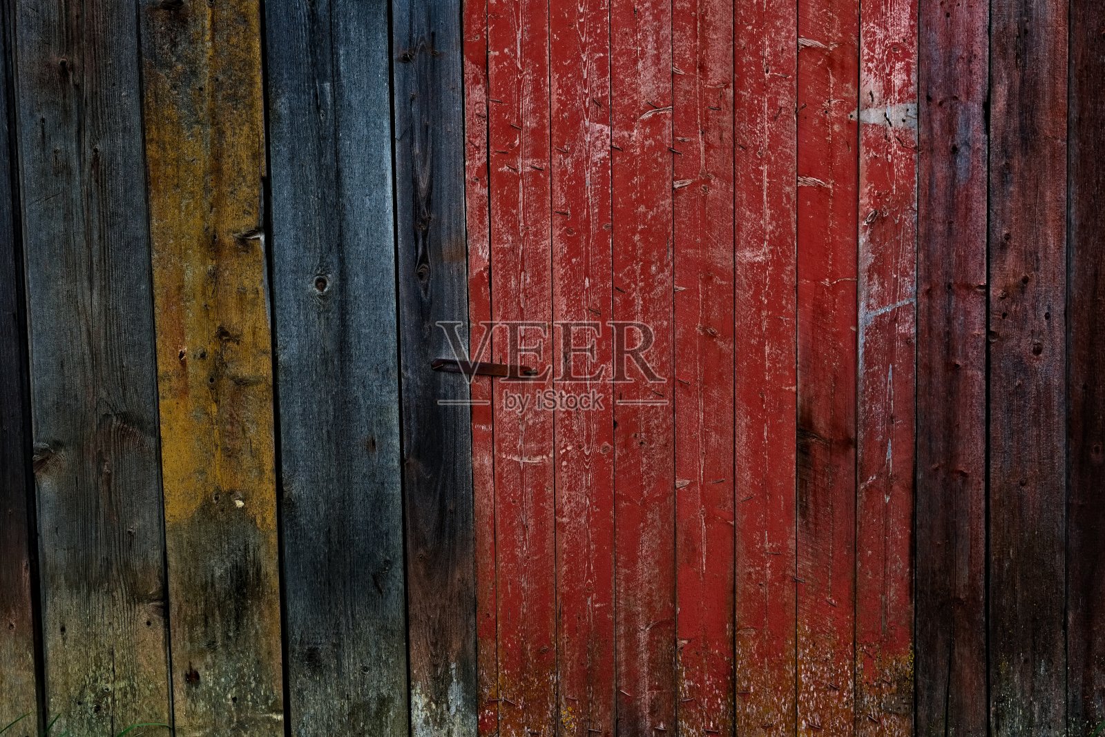 破旧的木板墙,局部涂有红色、蓝色和黄色的强调漆。照片摄影图片