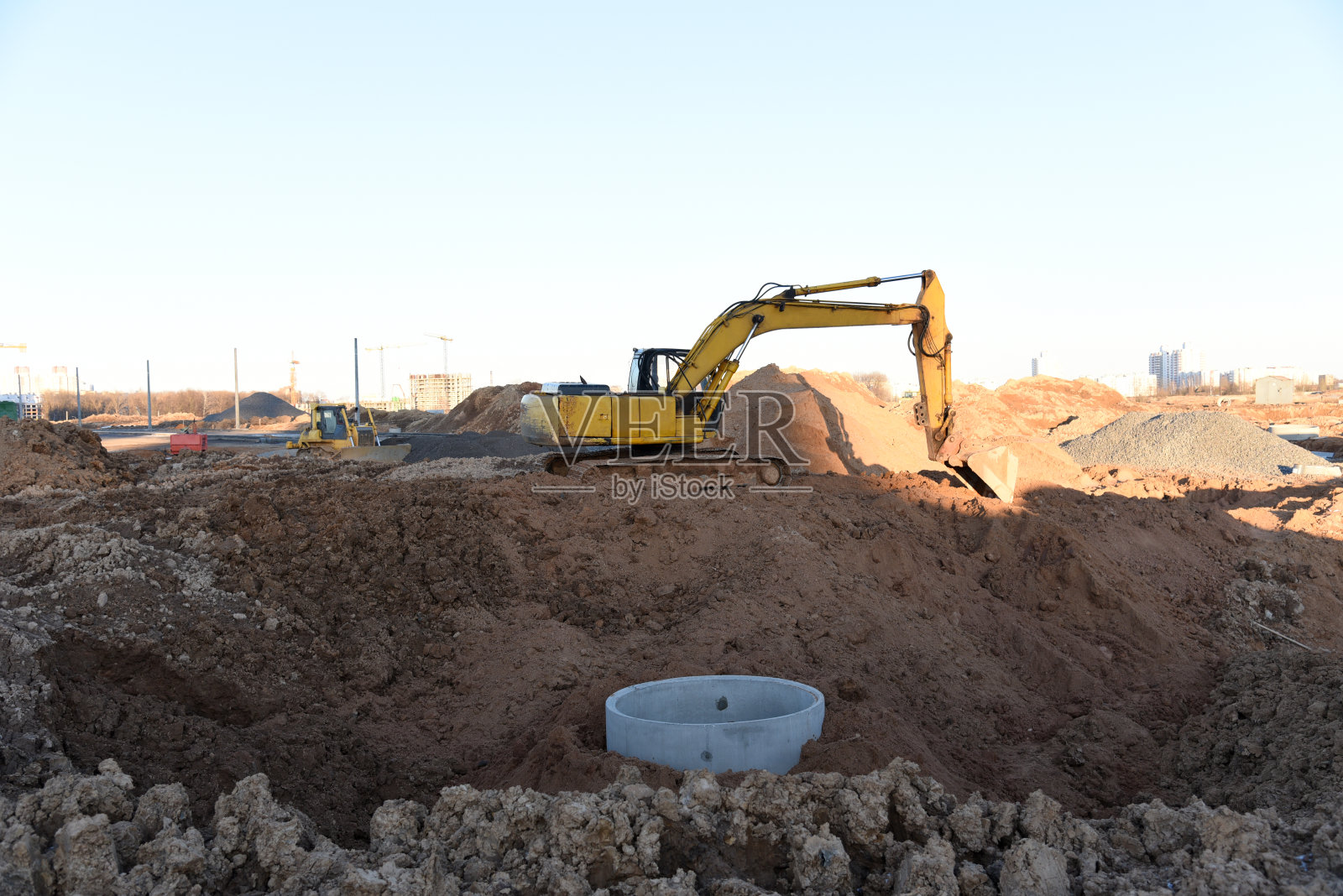 挖掘机在建筑工地挖战壕。敷设外部污水管的沟渠照片摄影图片