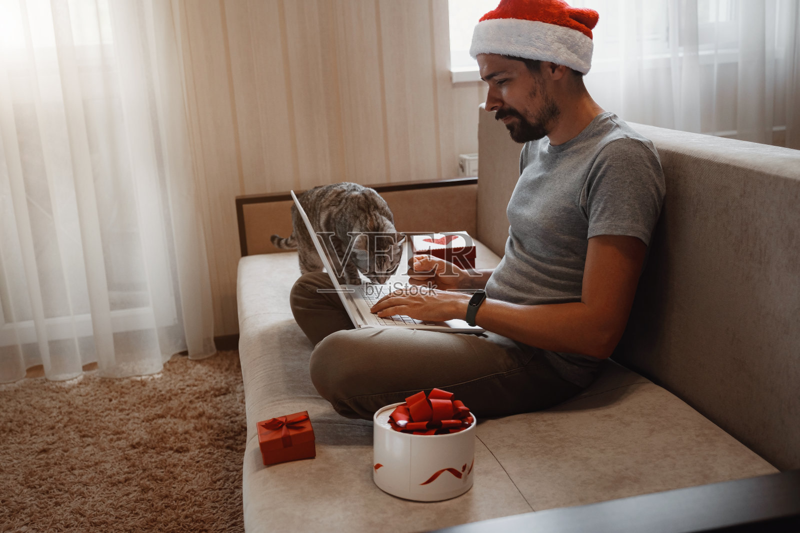 一个拿着红杯子坐在家里过圣诞节的潮人。照片摄影图片