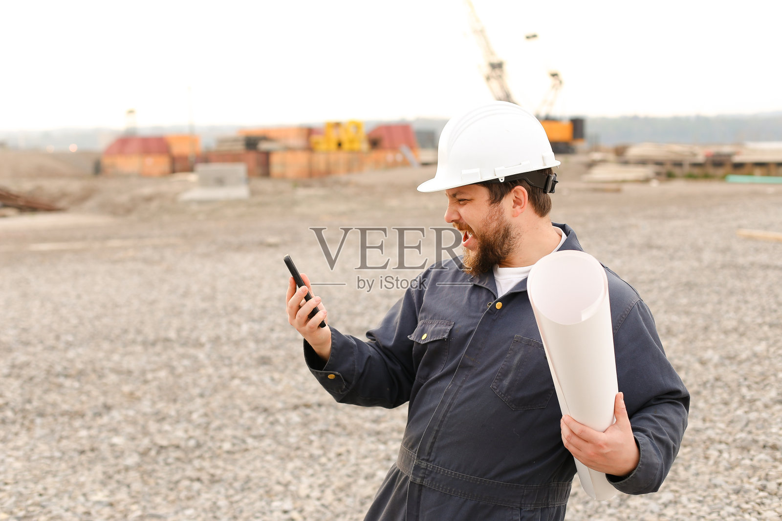 白人建筑工程师手持甚高频对讲机和文件在建筑工地照片摄影图片