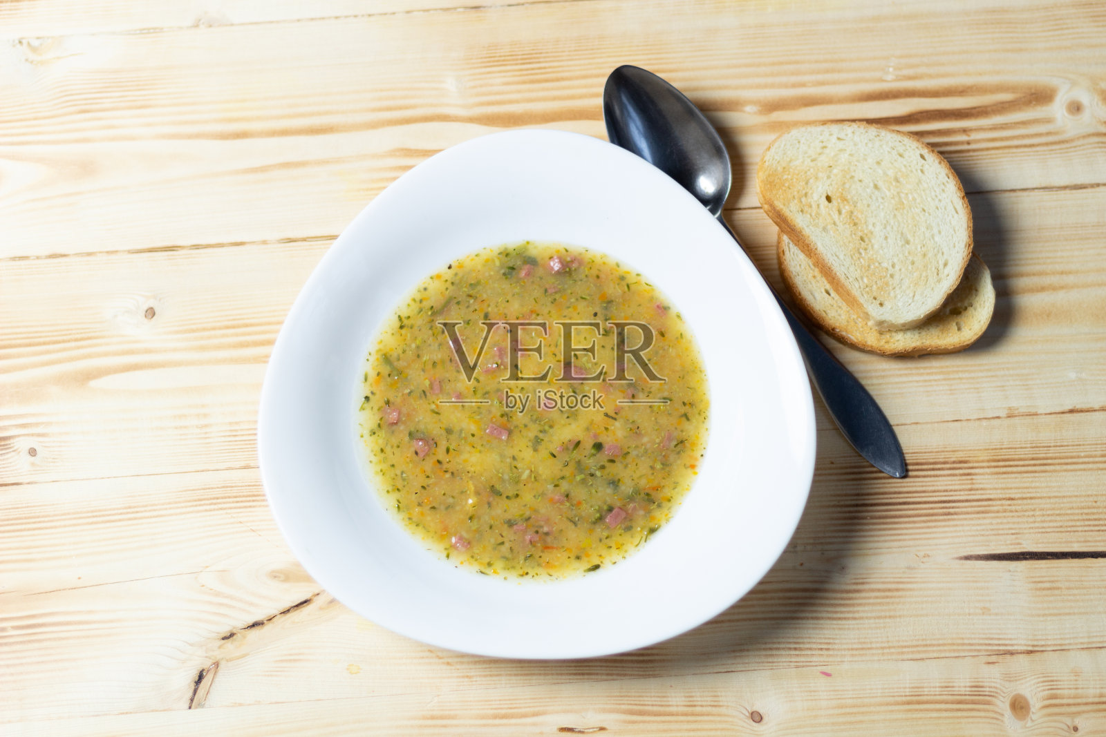奶油蔬菜汤,酸奶油,吐司,勺子在白色盘子在木制背景照片摄影图片