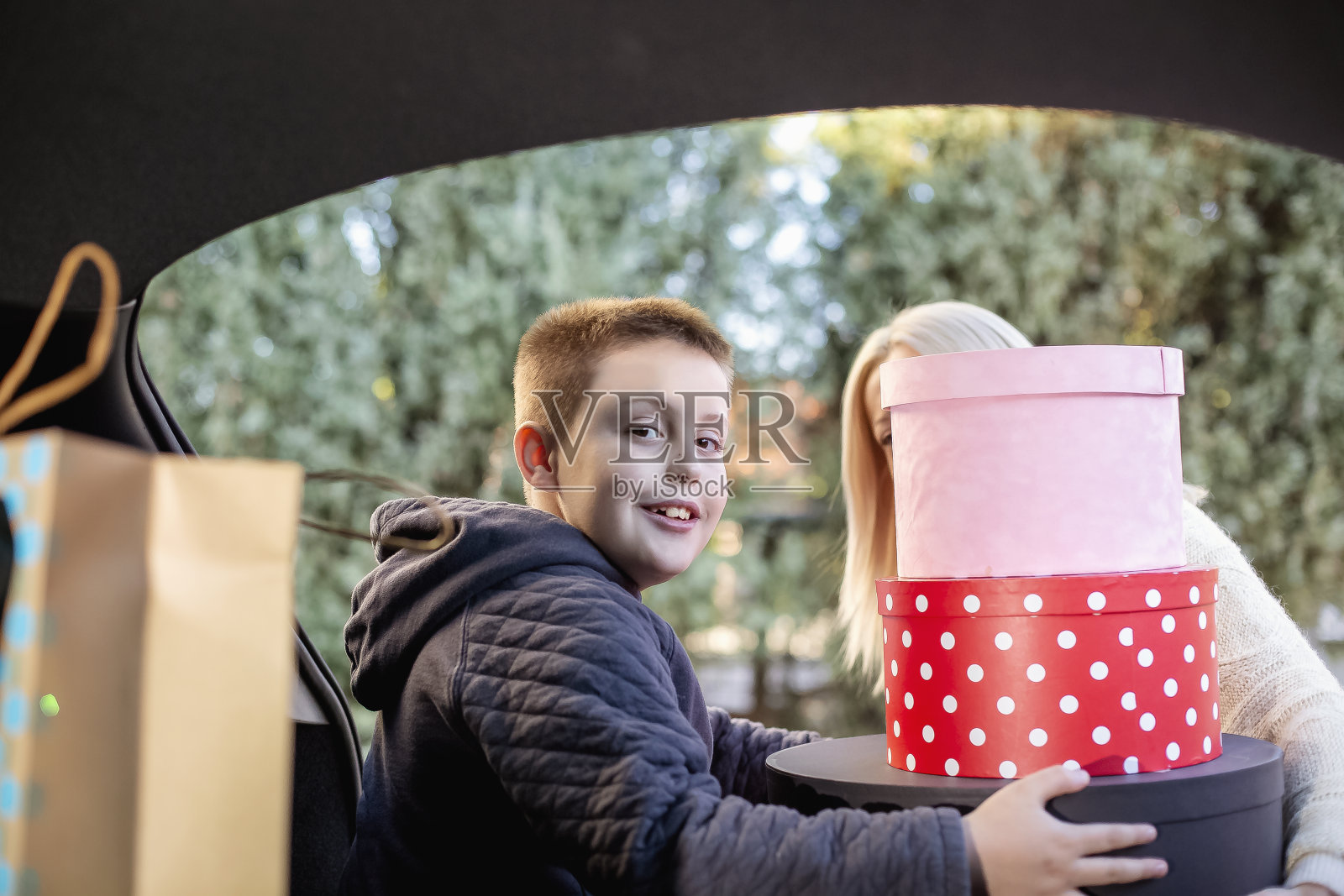 母亲和儿子在汽车后备箱里包装圣诞礼物照片摄影图片