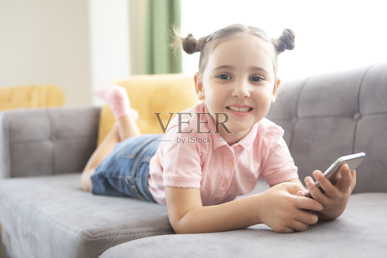 沙发上拿着手机的小女孩照片摄影图片