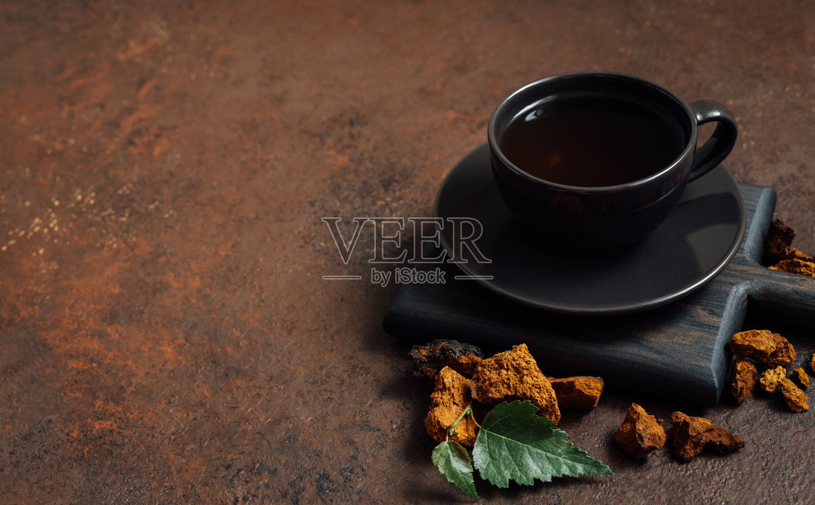 天然查加蘑菇咖啡在一个黑色的杯子在一个棕色的背景。健康美味的饮料。照片摄影图片