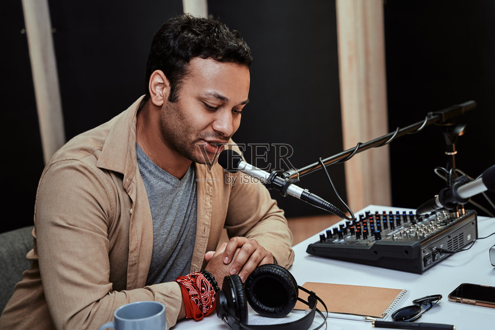 这是一幅年轻男性电台主持人在现场直播时的肖像,在麦克风里说话,坐在演播室里读稿子照片摄影图片