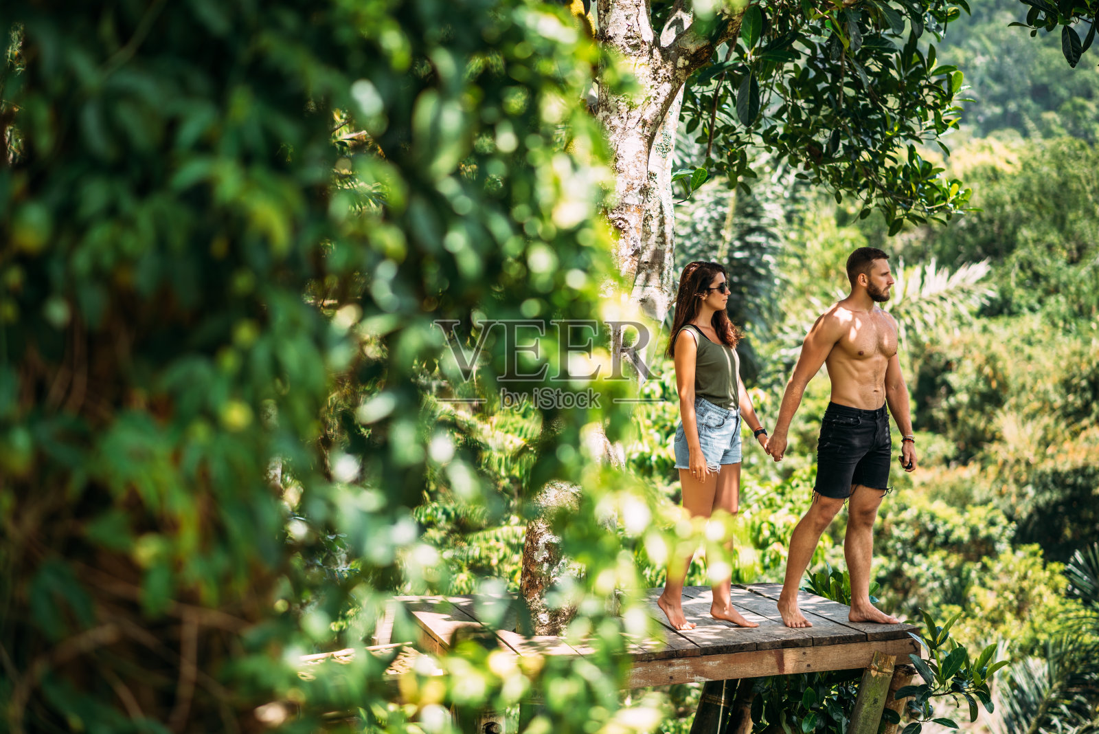 一对夫妇在绿树之间。一对在热带热恋的情侣。这对夫妇正在亚洲旅行。一对在巴厘岛旅游的美丽夫妇。以自然为背景的男人和女人。本空间照片摄影图片