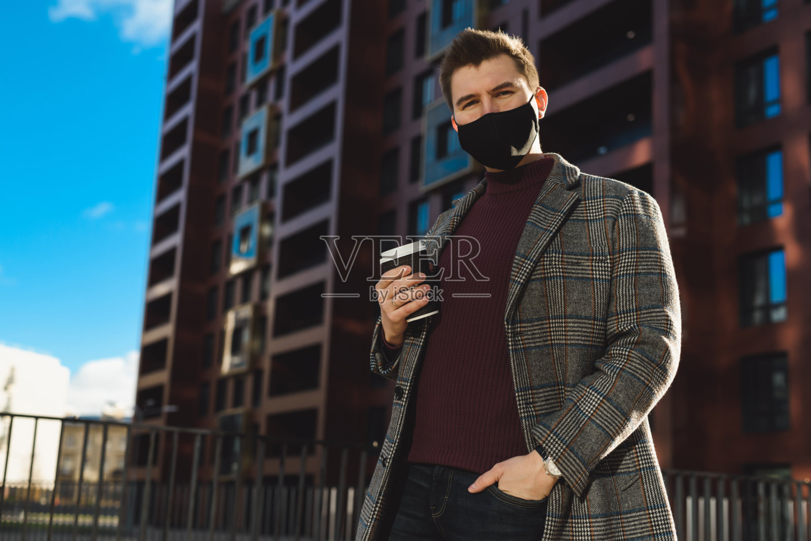 一个年轻的商人或经理和一杯咖啡的肖像。新冠肺炎大流行期间大城市的社交距离。在公共场所戴口罩。照片摄影图片