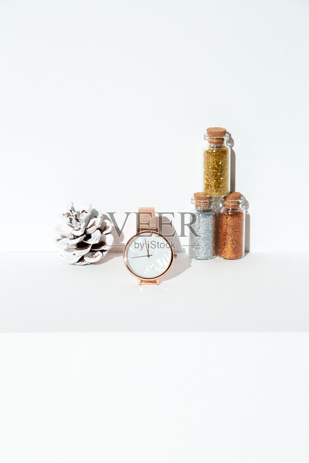 手表,亮片瓶子和云杉装饰的白色空间。新年、节日、圣诞节概念。极简主义,静物艺术照片摄影图片