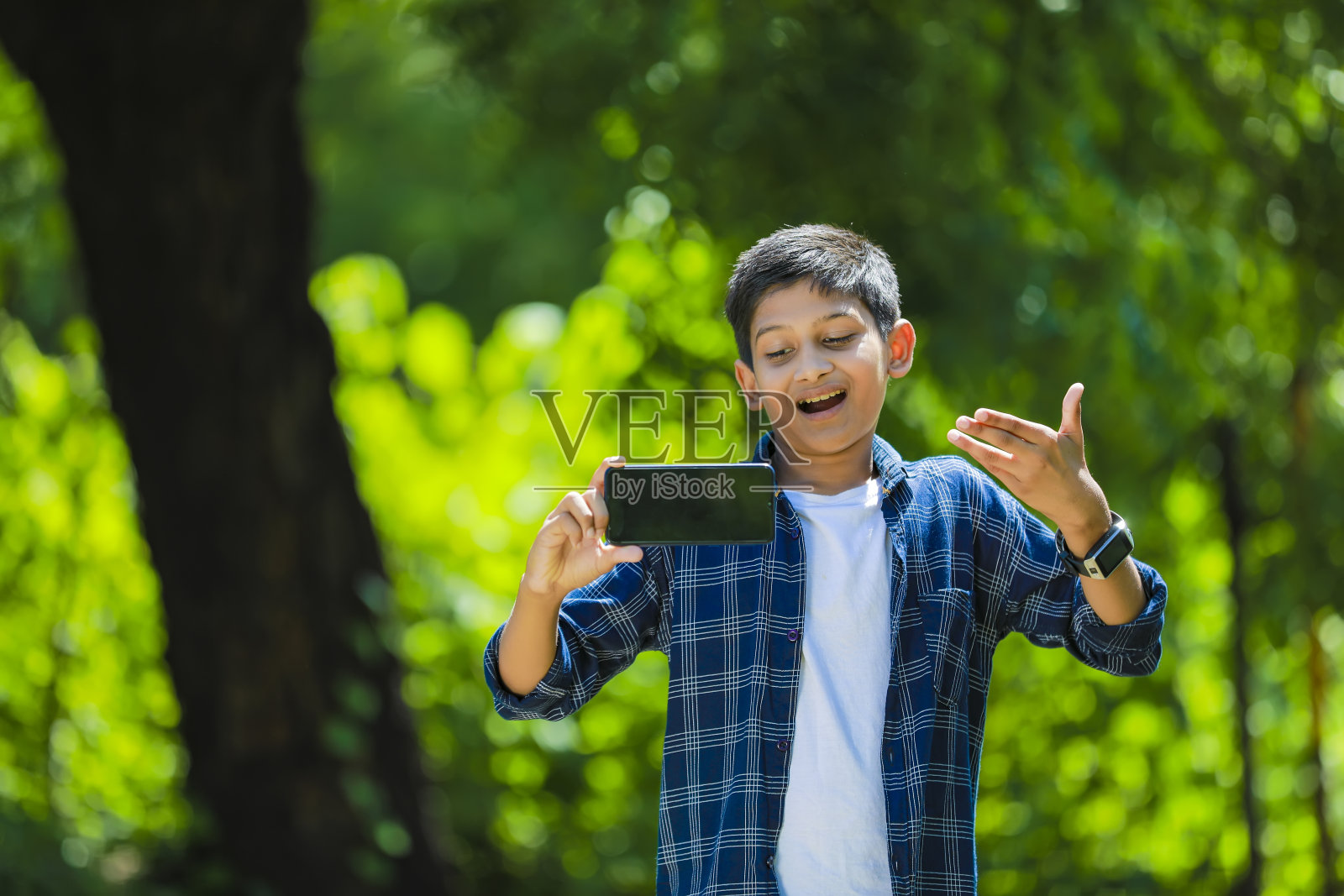科技和人的概念-微笑的青少年男孩在蓝色衬衫展示智能手机与空白屏幕照片摄影图片