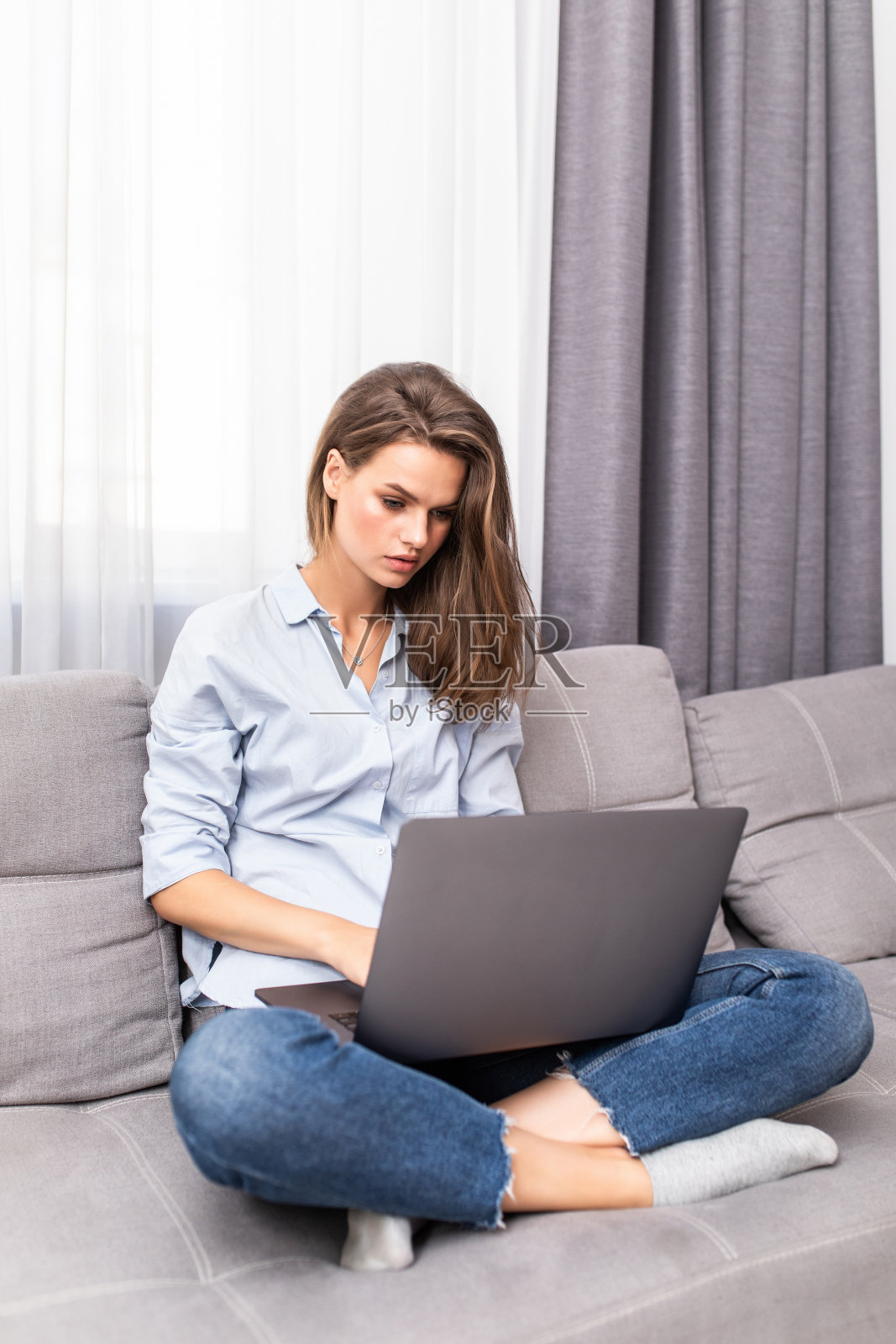 年轻漂亮的女人在沙发上休息的时候用着笔记本电脑照片摄影图片