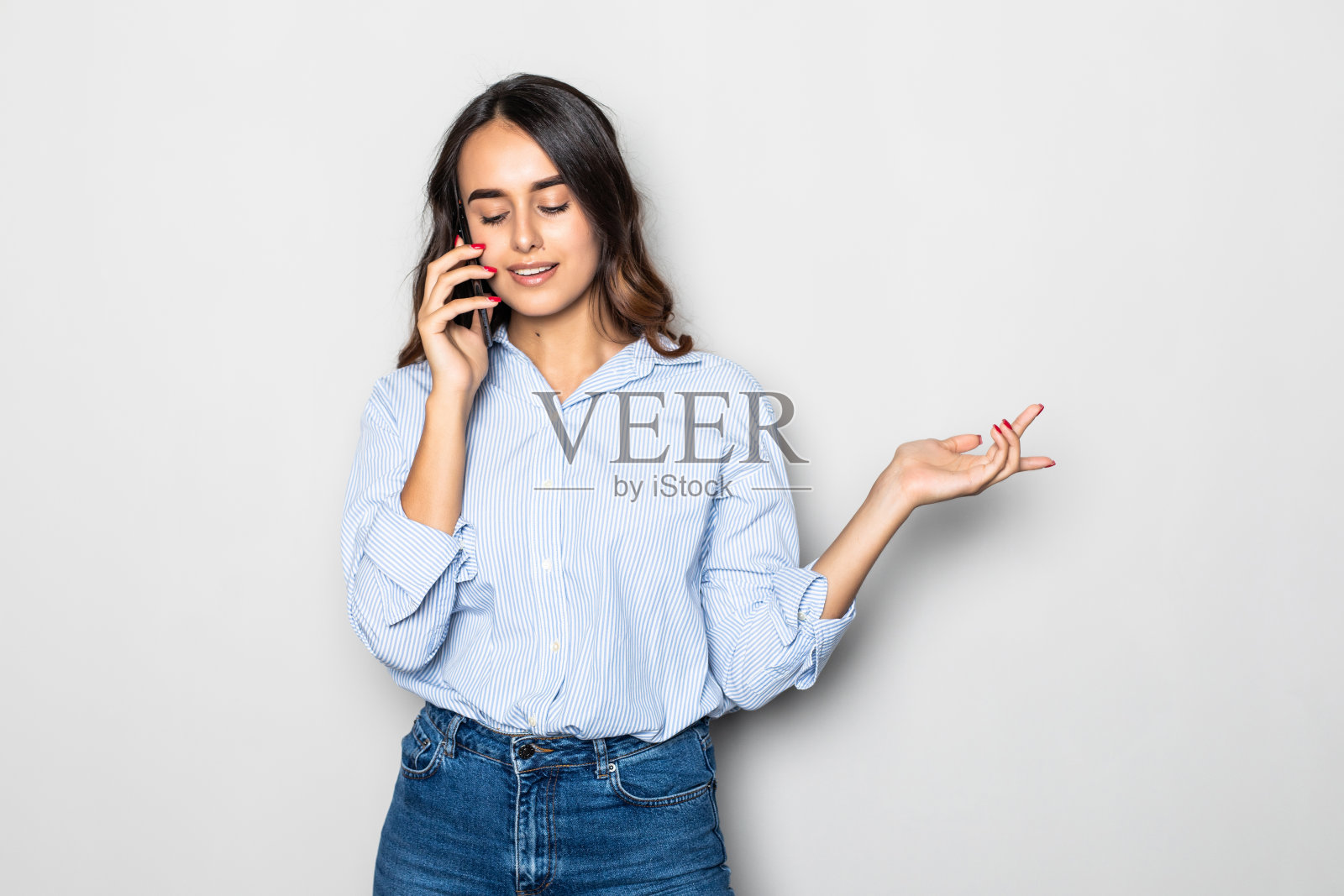 年轻漂亮的少女在灰色背景下用智能手机和她最好的朋友聊天照片摄影图片