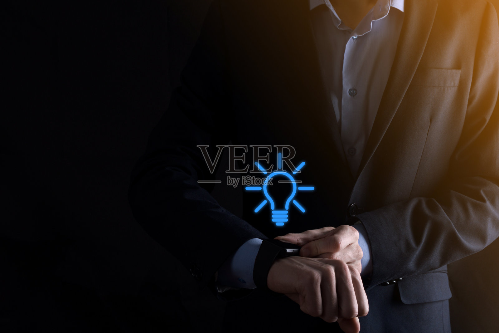 穿着西装,手里拿着灯泡的商人。手里拿着一个发光的图标。与文本的位置照片摄影图片