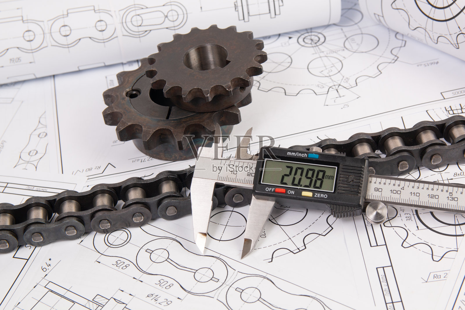 在工程图纸上驱动工业滚子链、数字卡尺和链轮照片摄影图片
