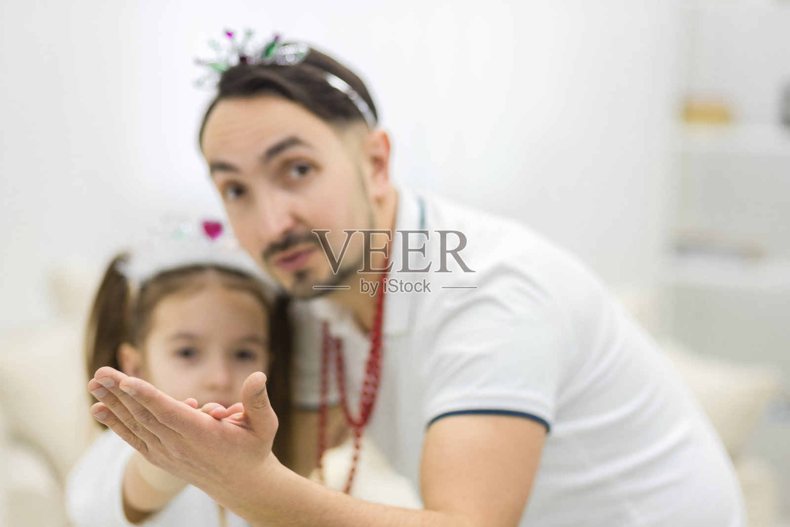 父亲和女儿戴着皇冠跳舞的特写照片。照片摄影图片