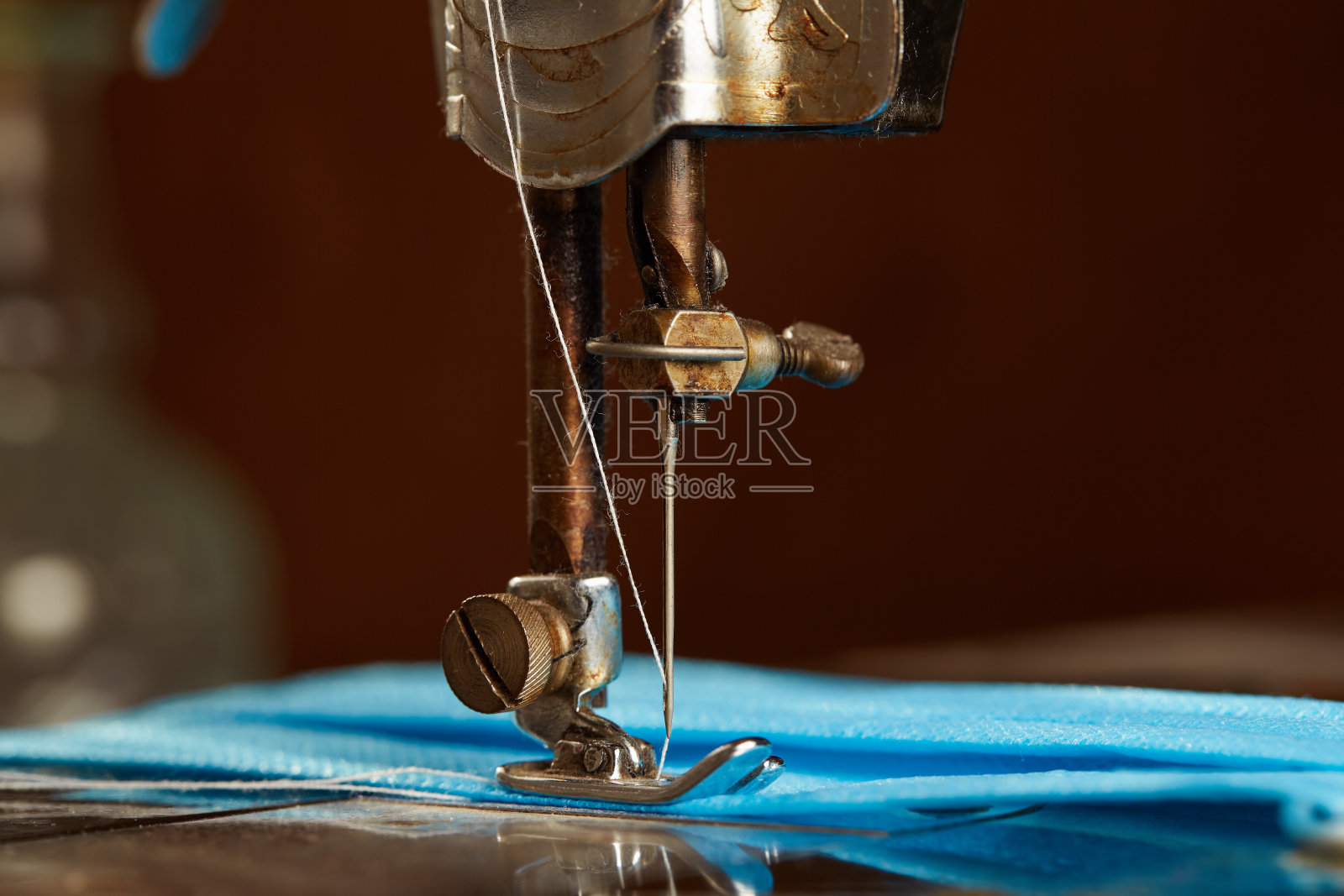 缝纫机的特写镜头,上面缝着一个蓝色的外科口罩照片摄影图片