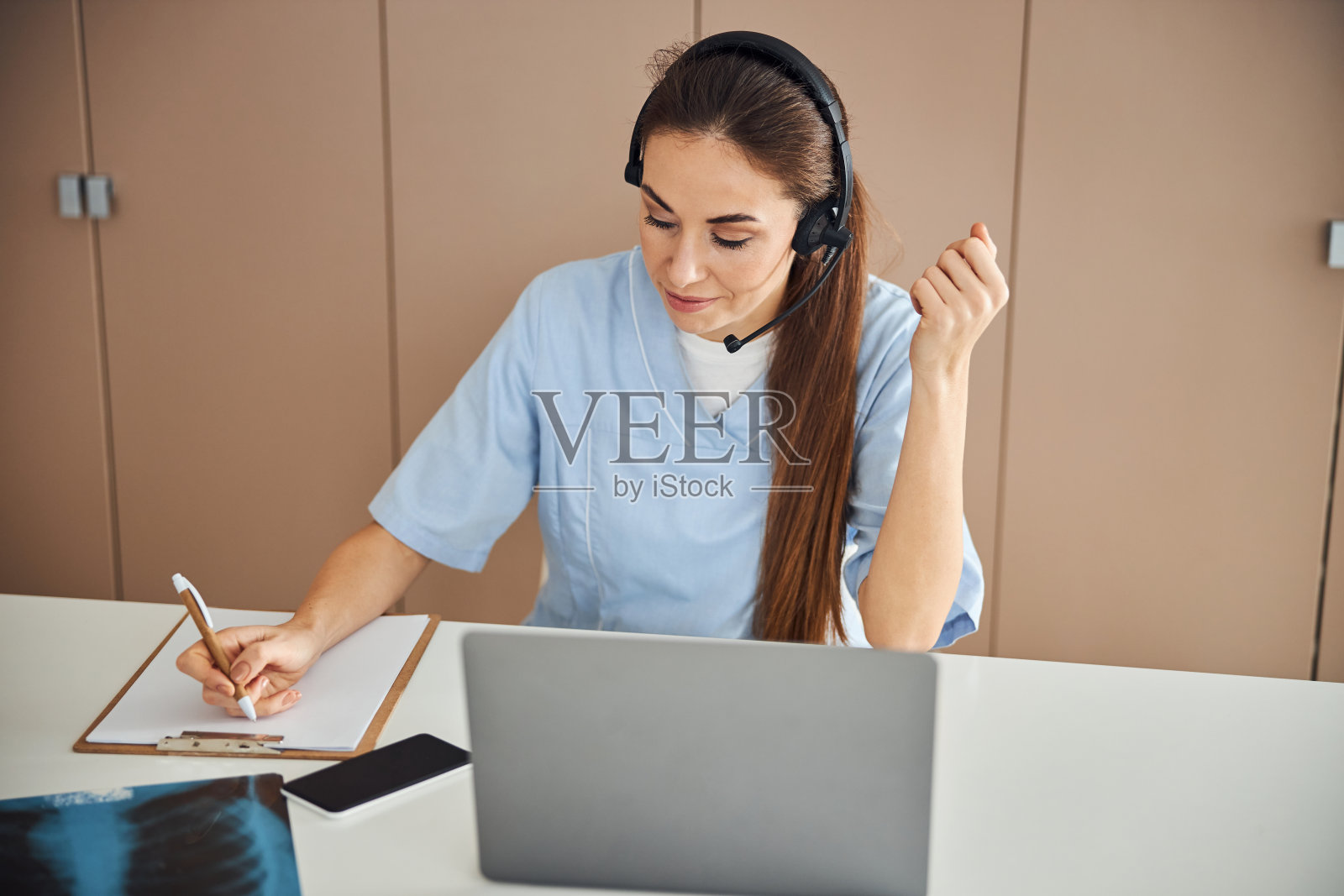 专注的深色头发的女士在医生制服写在纸上照片摄影图片