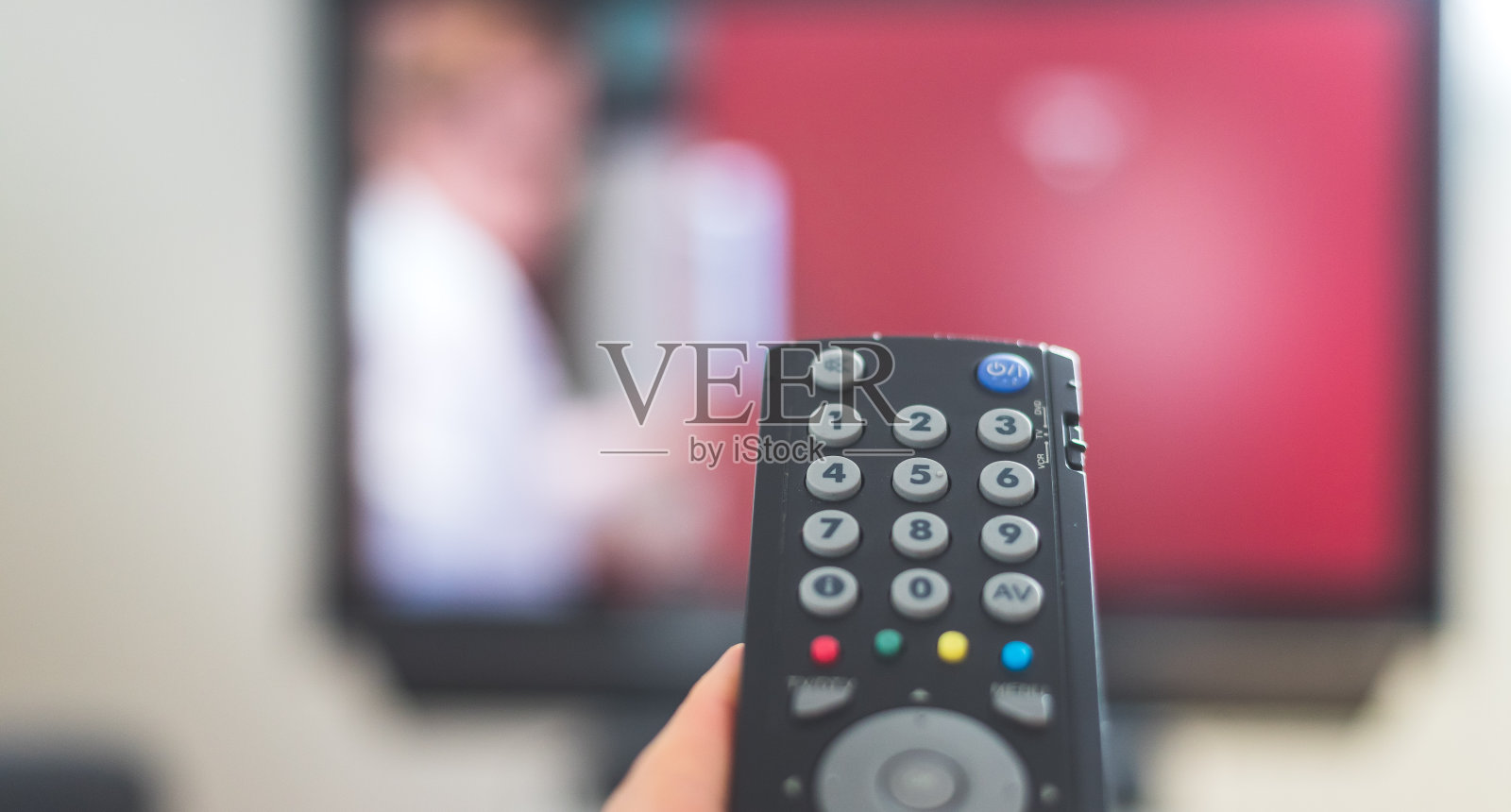 男性的手正握着电视遥控器,在智能电视上流媒体。照片摄影图片