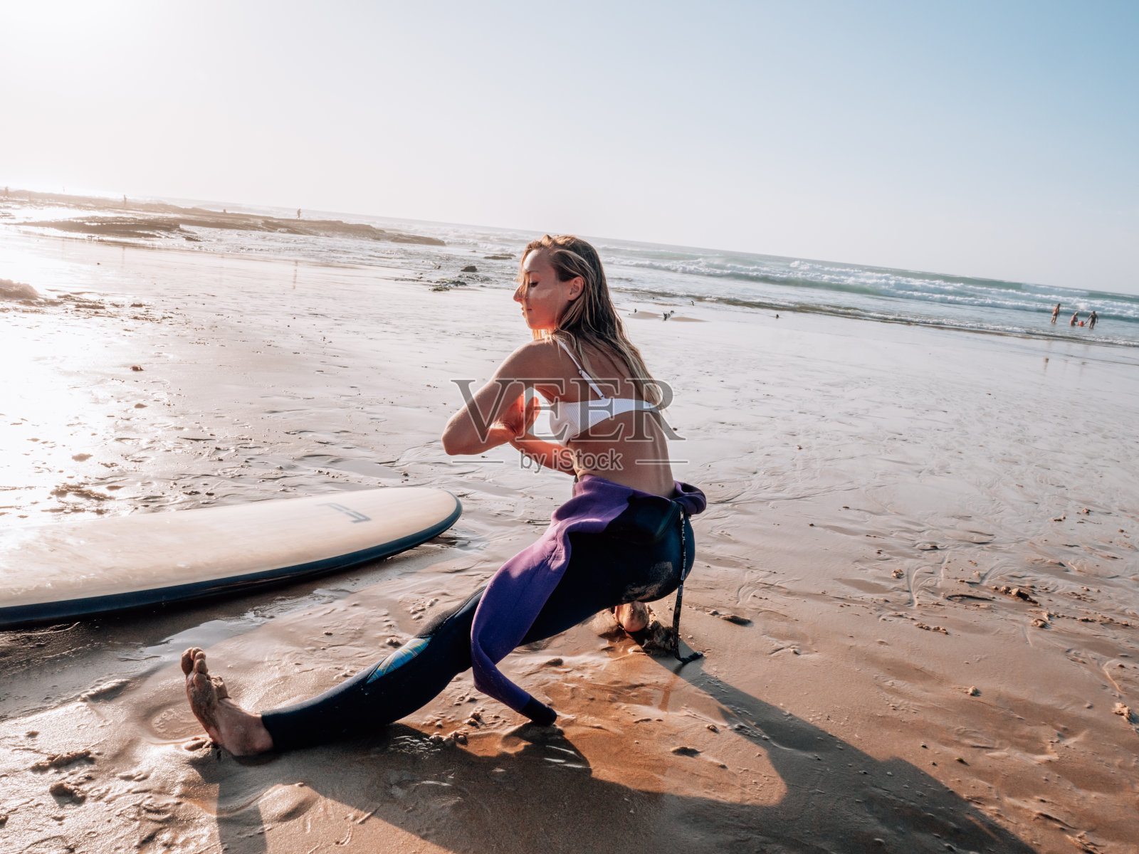 日出时,冲浪者在海滩上伸展四肢照片摄影图片