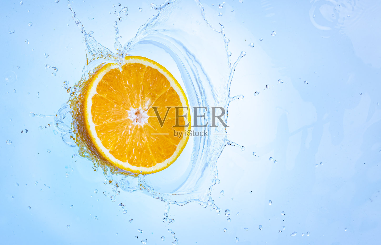 新鲜的、成熟的一半橙子飞溅到清澈的水中。照片摄影图片