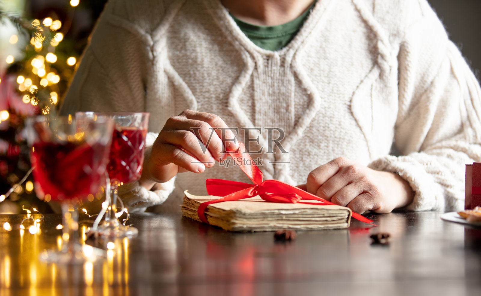 一个人坐在桌旁打开一本旧书的箱子,作为圣诞节礼物照片摄影图片